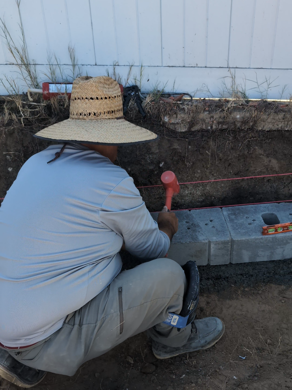 Setting the First Course of a Retaining Wall: Base Block Leveling & Concrete Footings in San Diego